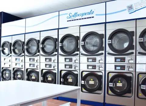 Fila di lavatrici e asciugatrici nella lavanderia self service Sottocoperta